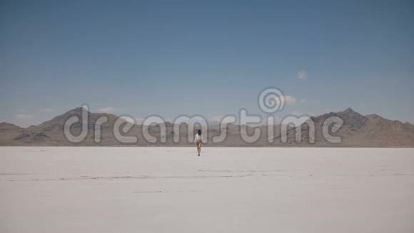 在犹他州的盐漠湖一个女人独自从遥远的地方走到镜头前拍摄的美丽背景照片视频的预览图