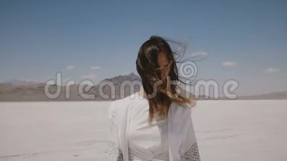 迷人的快乐女人穿着轻便休闲的夏季服装摆姿势走向相机在犹他州的热盐沙漠湖视频的预览图