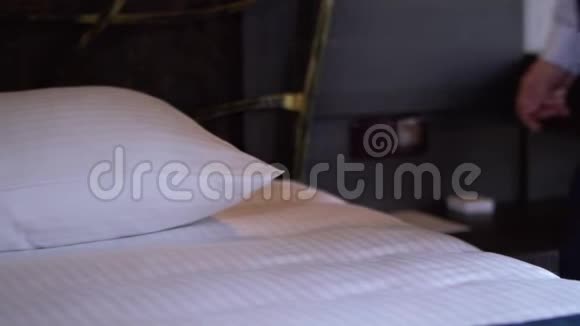一位酒店清洁女士在一间舒适的小酒店房间里伸直了枕头视频的预览图
