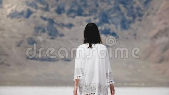 后景年轻快乐自由的当地妇女步行到史诗山举臂在盐漠湖自由的概念视频的预览图