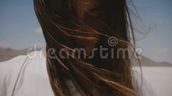超级特写生活方式肖像幸福的年轻女子微笑在相机与飞行头发和牙套在盐湖视频的预览图