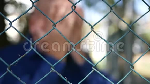 令人失望的男子用模糊的射击在金属围栏后面视频的预览图