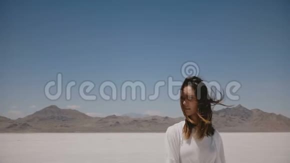 令人惊叹的生活方式肖像快乐的年轻女子行走微笑的相机与飞行的金色头发在盐漠湖视频的预览图