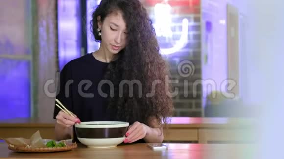 一个可爱的年轻亚洲女孩在亚洲咖啡馆的智能手机pho汤上拍照中文越南文或日文视频的预览图
