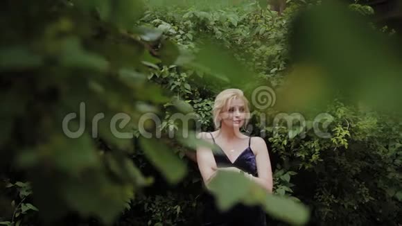 美丽的女人照片模型站在绿色灌木丛在夏天视频的预览图