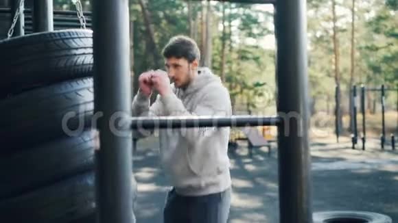 大胡子的家伙是一个人在户外拳击使用轮胎在运动场锻炼在夏季的一天锻炼身体视频的预览图