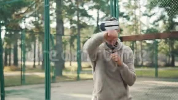 男学生在公园训练时戴着虚拟现实眼镜和拳击独自享受活动和现代视频的预览图