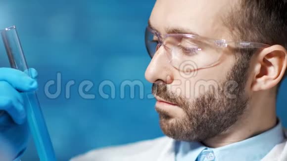男性化学家用蓝色物质制作烧杯有实验室特写镜头的经验视频的预览图