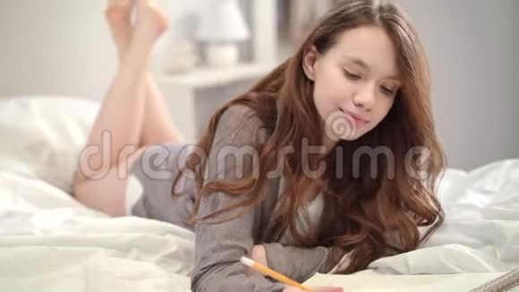 温柔的女人在床上用铅笔思考快乐的模特在床上写铅笔视频的预览图