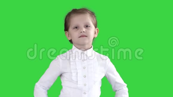 可爱的小女孩穿着白色连衣裙在绿色屏幕上的相机上摆姿势Chroma键视频的预览图
