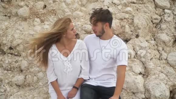 年轻漂亮的一对夫妇站在大石头附近谈话视频的预览图