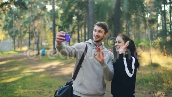有魅力的女人和男人在运动训练后在公园里用智能手机进行在线视频通话有人拿着视频的预览图