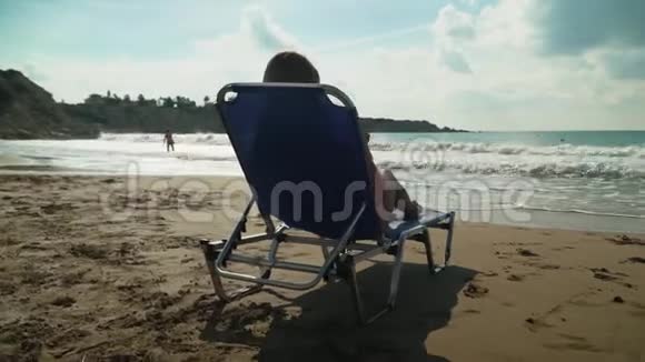 金发女人在海滩上晒日光浴躺在甲板椅上海边近在咫尺戴墨镜的女孩崇拜美丽视频的预览图