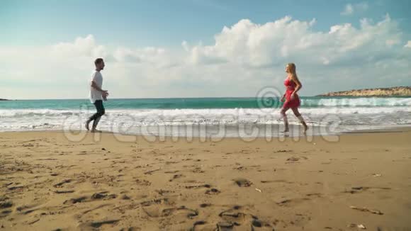 年轻人和女人在海滩上互相跑来跑去男人把穿着衣服的女孩抱在怀里转悠视频的预览图
