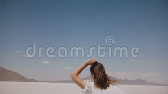 后景美丽快乐自由的女人向前奔跑手臂张开飞扬的头发在盐漠湖邦尼维尔犹他州视频的预览图