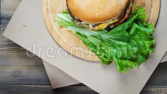 提供新鲜多汁汉堡和奶酪酱汁和蔬菜并在木制桌子上旋转视频的预览图