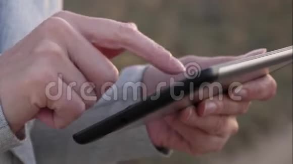 女孩的手在智能手机屏幕上打印一条移动信息女孩手指触摸屏的平板电脑智能手机关闭视频的预览图