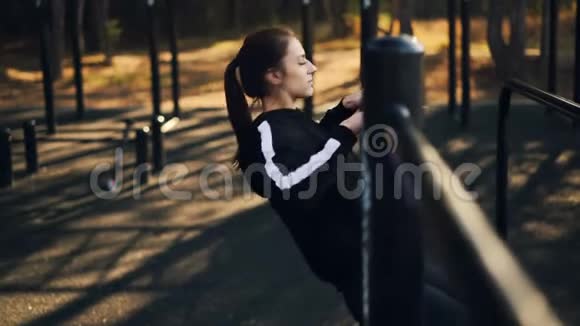 适合的年轻女子在户外运动独自在公园的低水平杆上做拉力练习视频的预览图