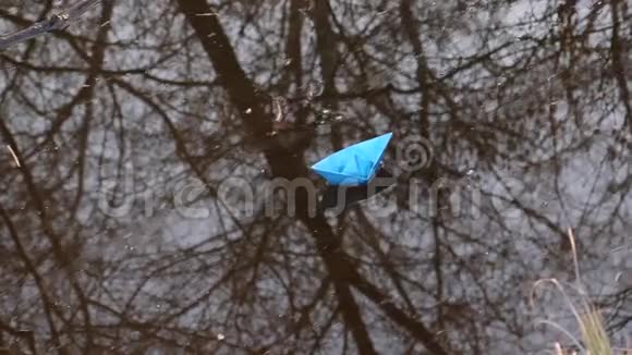 蓝色和棕色的纸船沿着春天公园的小溪漂浮着视频的预览图