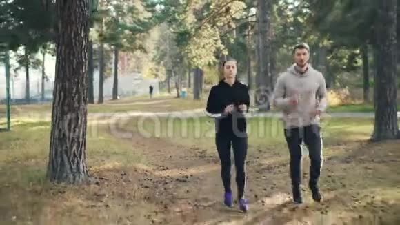在公园里一起慢跑的迷人女孩和男人的多利照片集中在练习上女人穿着运动衫视频的预览图