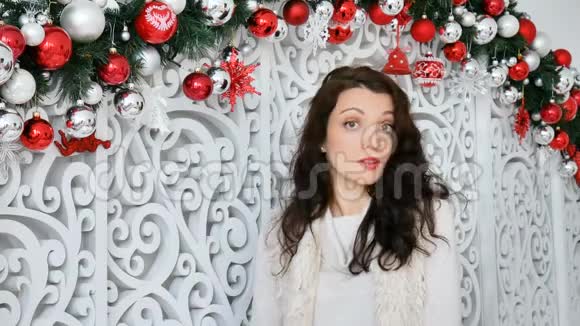 漂亮的女人一张严肃的脸正带着一些东西在圣诞节装饰的背景上看着相机视频的预览图