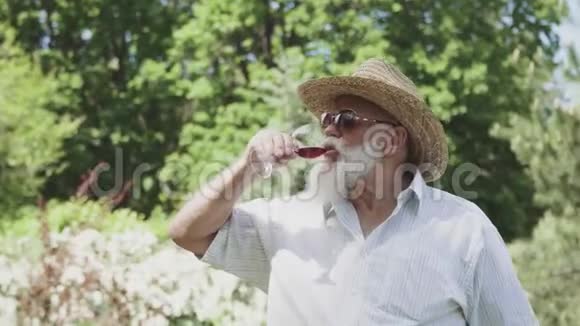 戴帽子的老人在户外喝红酒的画像视频的预览图