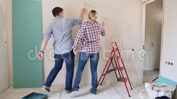 有趣的年轻夫妇在墙上画画在房子里做装修时跳舞玩得开心视频的预览图