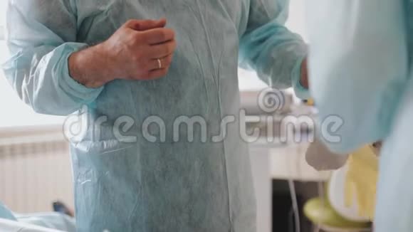 外科医生在助手的帮助下戴手套视频的预览图