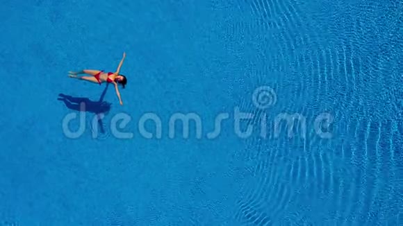 从顶部看一个穿红色泳衣的女人在游泳池里仰泳视频的预览图