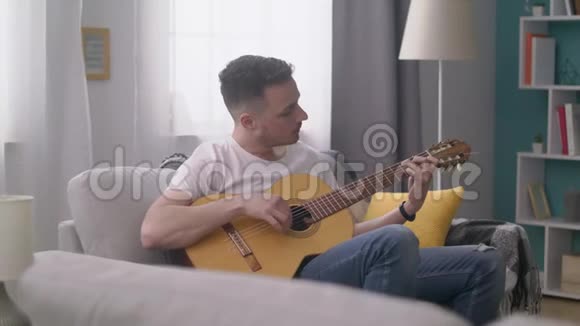 恐慌的年轻人在他舒适的客厅里弹吉他视频的预览图