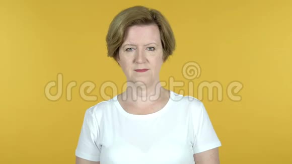 老女人在黄色背景下采集拇指视频的预览图
