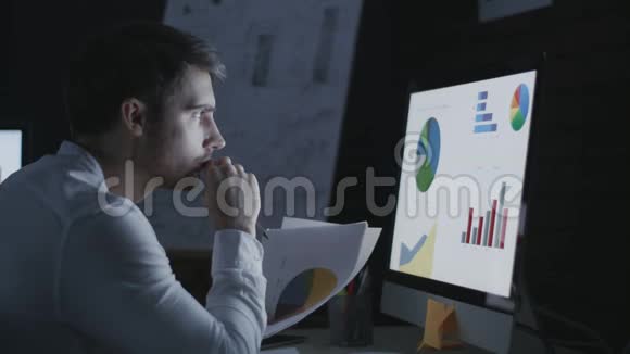 集中业务人员在夜间办公室分析财务文件视频的预览图