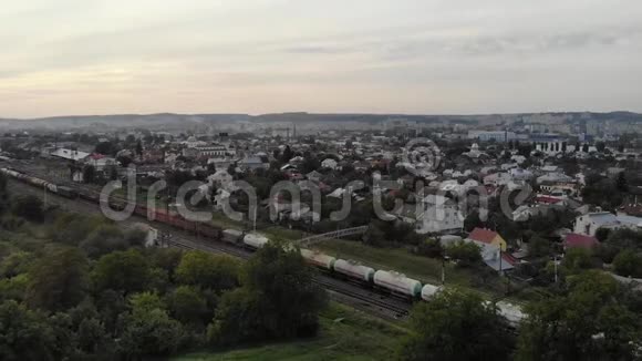 货运列车在私人住宅间的乡村景观中滚动鸟瞰视频的预览图