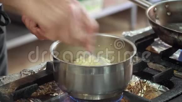 厨师在煤气炉上搅动砂锅里的配料手的特写动作视频的预览图