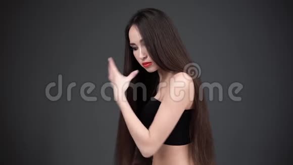 年轻女人用梳子梳头发有着豪华头发的女人在微笑深色背景视频的预览图