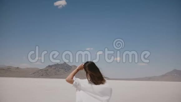 镜头跟随年轻快乐的自由女人向前奔跑头发在阳光明媚的盐湖吹在犹他州视频的预览图
