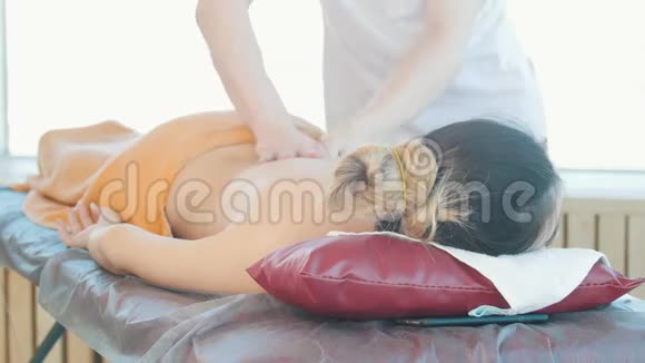 按摩会年轻女子躺在沙发上接受放松的背部按摩视频的预览图