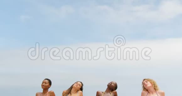 在海滩上闭着眼睛放松的混血女性朋友的正面景色视频的预览图
