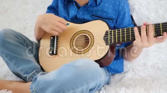 一个孩子把小吉他弹得很近弹吉他唱歌音乐教育节奏视频的预览图