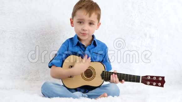 那个淘气的男孩坐在沙发上弹吉他那孩子唱歌音乐教育声乐视频的预览图