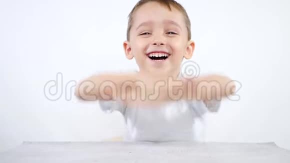 一个小淘气坐在桌子旁笑着看着镜头一个真诚地笑的男孩的肖像视频的预览图