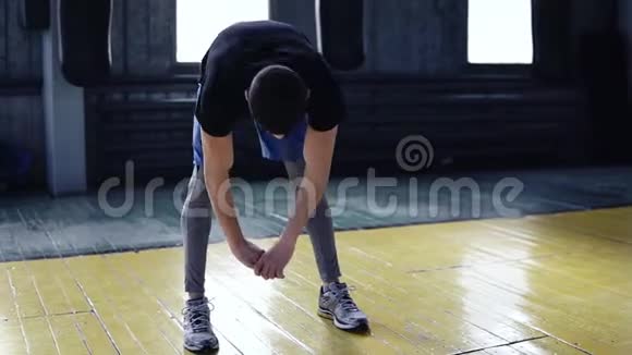 年轻的运动员在室内训练的男拳击手躯干倾斜双手伸展到地板上在主机前热身视频的预览图