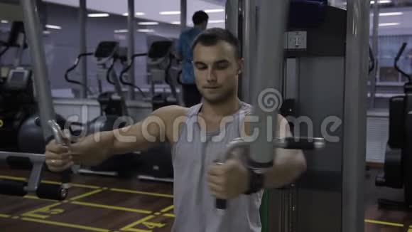 年轻人正在室内健身房训练PecDeck机器视频的预览图