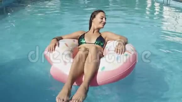 快乐的女人在游泳池里漂浮着一个充气的甜甜圈视频的预览图