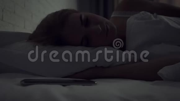睡眼的女人在早晨醒来时会关掉警报视频的预览图