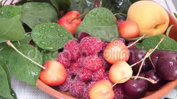樱桃杏果和带水滴和绿叶的覆盆子视频的预览图