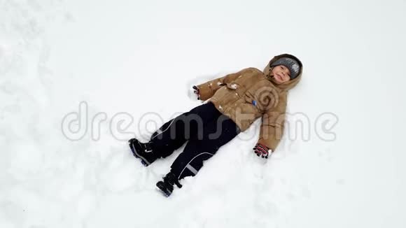 4k视频快乐的托德勒男孩躺在雪地公园笑视频的预览图