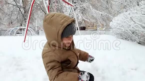 雪后在冬季公园的操场上扔雪球的快乐微笑幼儿男孩视频视频的预览图