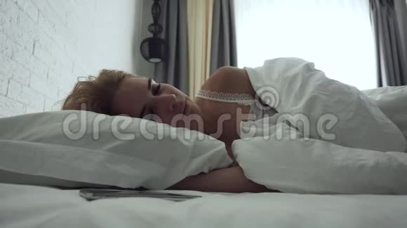 睡眼的女人在早晨醒来时会关掉警报视频的预览图