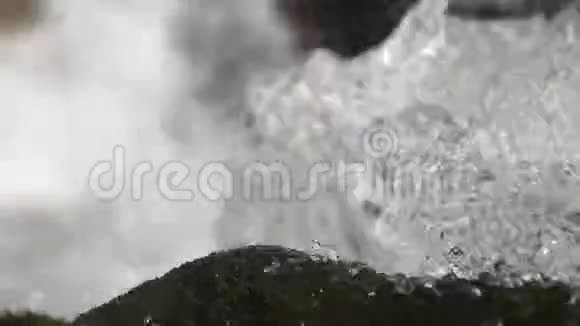 水流向下流过悬崖和岩石靠近瀑布附近的小溪里泼水清澈的河水视频的预览图